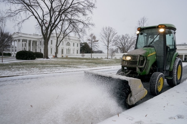 La Casa Blanca también amaneció con una capa de nieve. Un trabajador del Servicio Nacional de Parques limpia los jardines (AP)